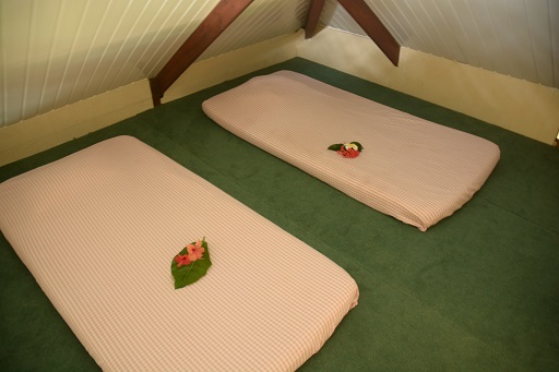 Chambre avec deux matelas futon, décorés de fleurs, sur un tapis vert dans un bungalow.