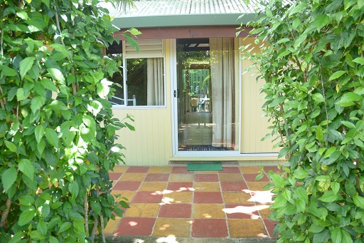 Entrée d'un bungalow avec des plantes vertes de chaque côté et un sol carrelé coloré.